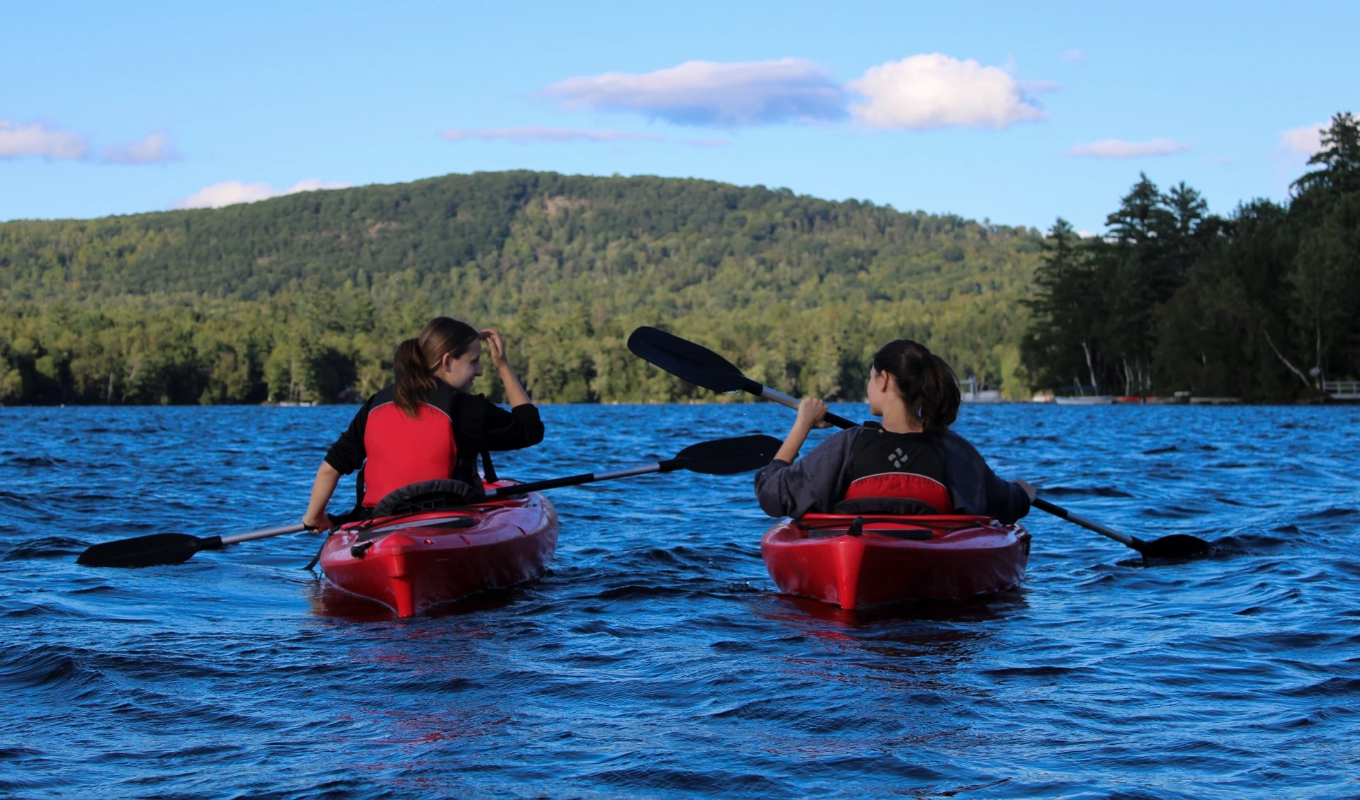 Two students kayaking with mountains in the background.