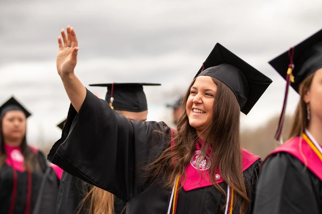 Smiling graduate student waving their hand
