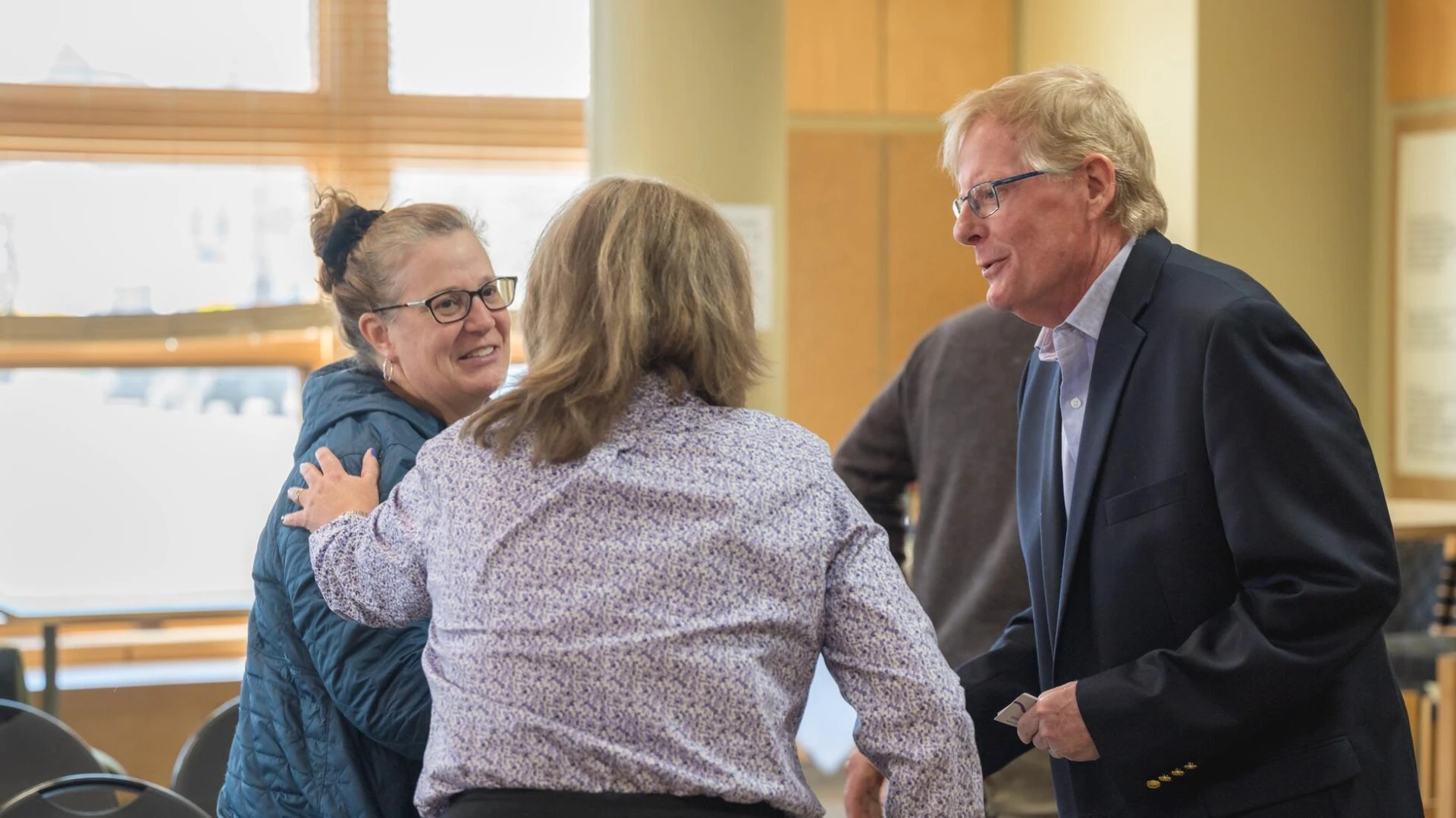three people talking with each other with one person putting their hand on another persons shoulder