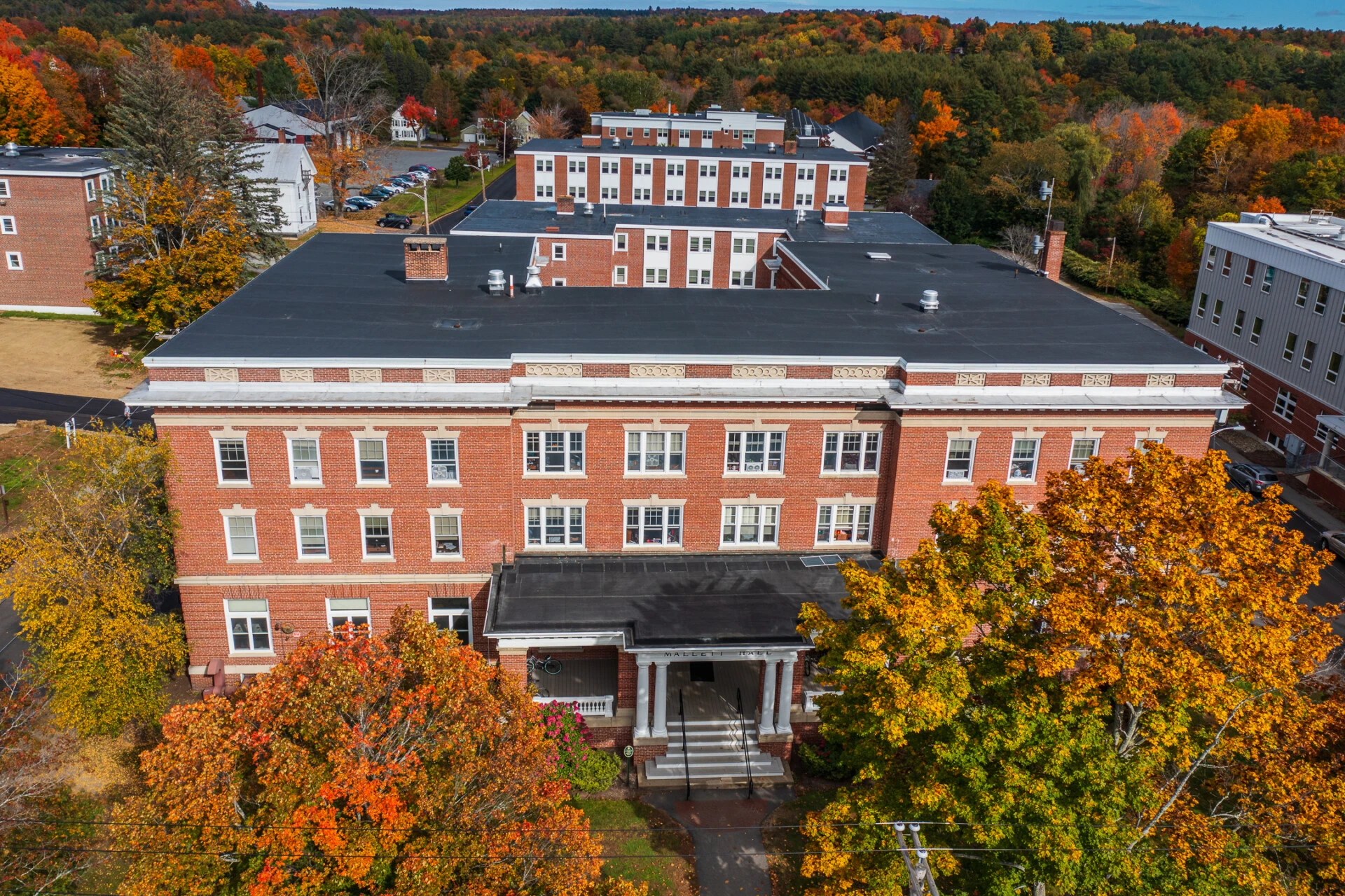 A photo of the Mallet dormitory with large trees in front.