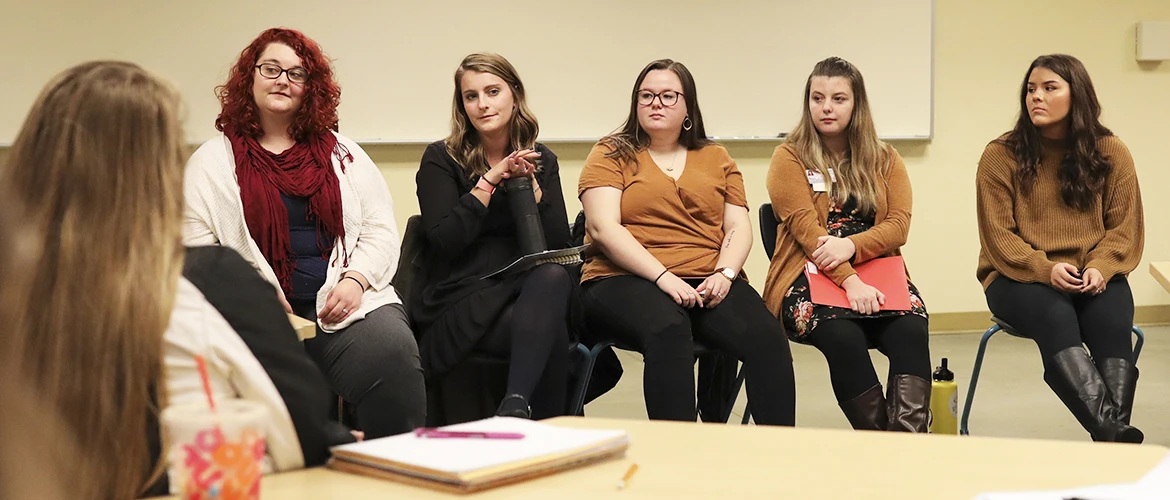 A group of graduate psychology students discuss in a circle.