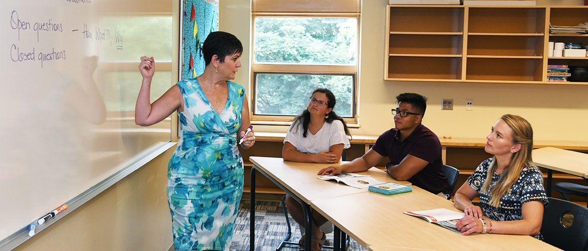 Counseling Psychology Creative Arts Focus UMF professor teaches class at whiteboard.