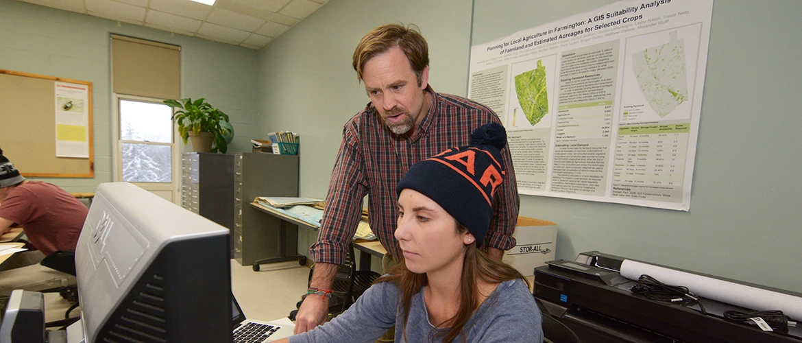 Geography and Environmental Planning student and professor discuss in classroom.