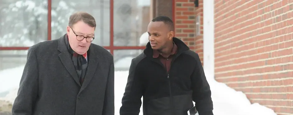 Graduate students walk on a snowy campus.