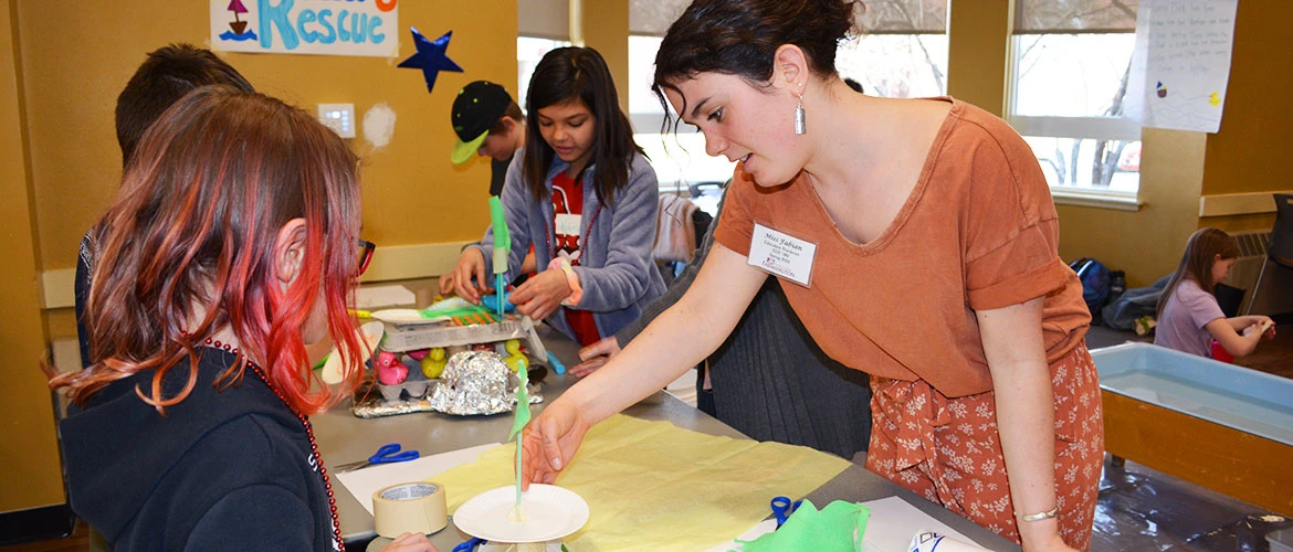 STEAM elementary ed student works with child in classroom.