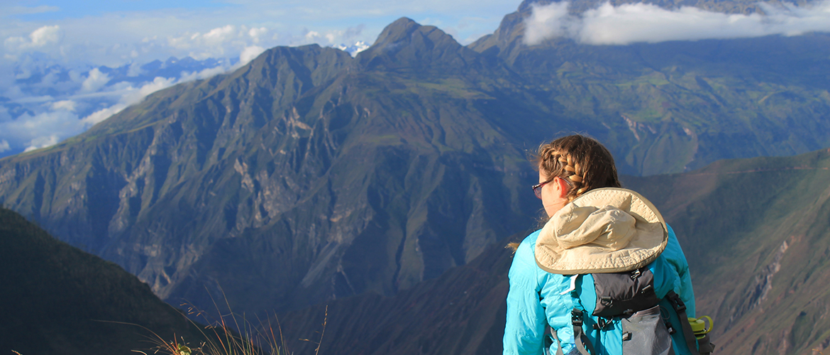 UMF student stands in front of mountain landscape.