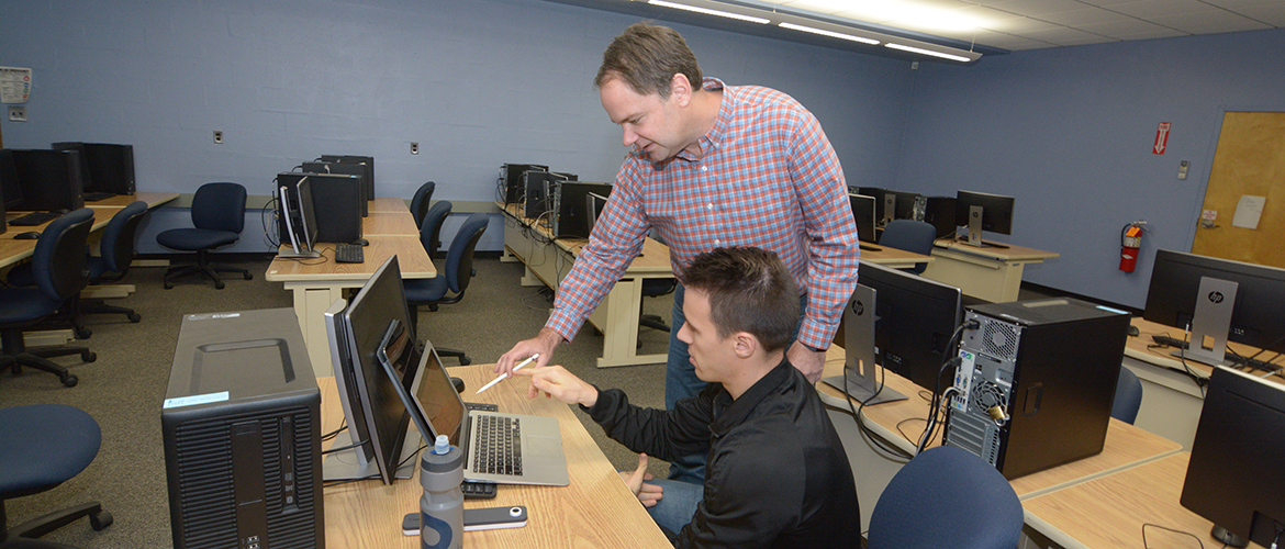 Student and professor work at computers.