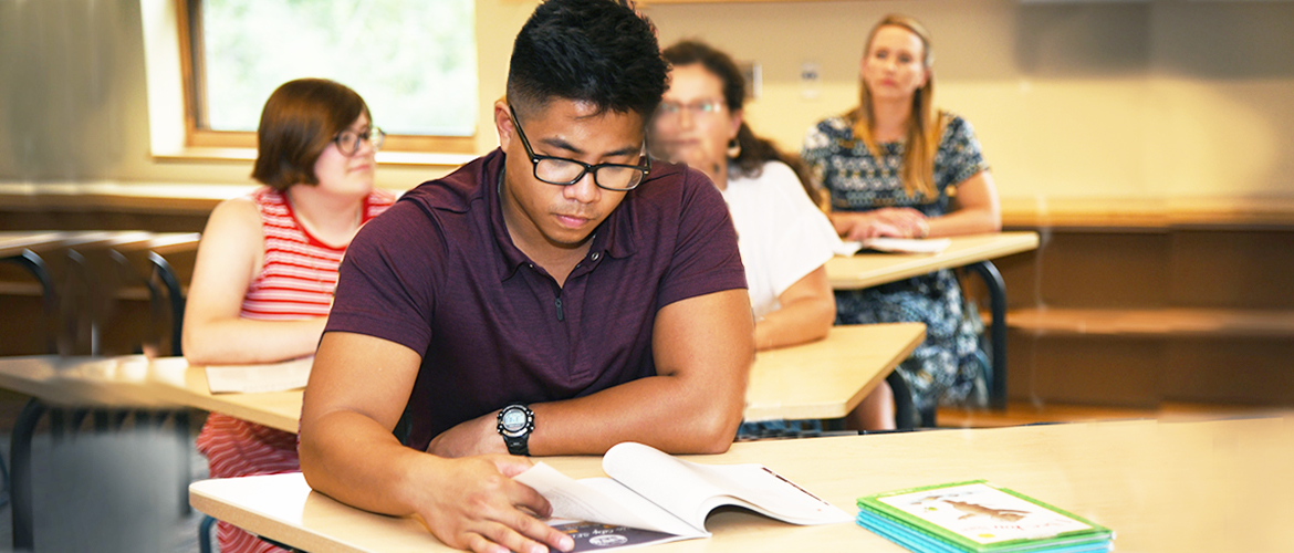 UMF student reads textbook in classroom.