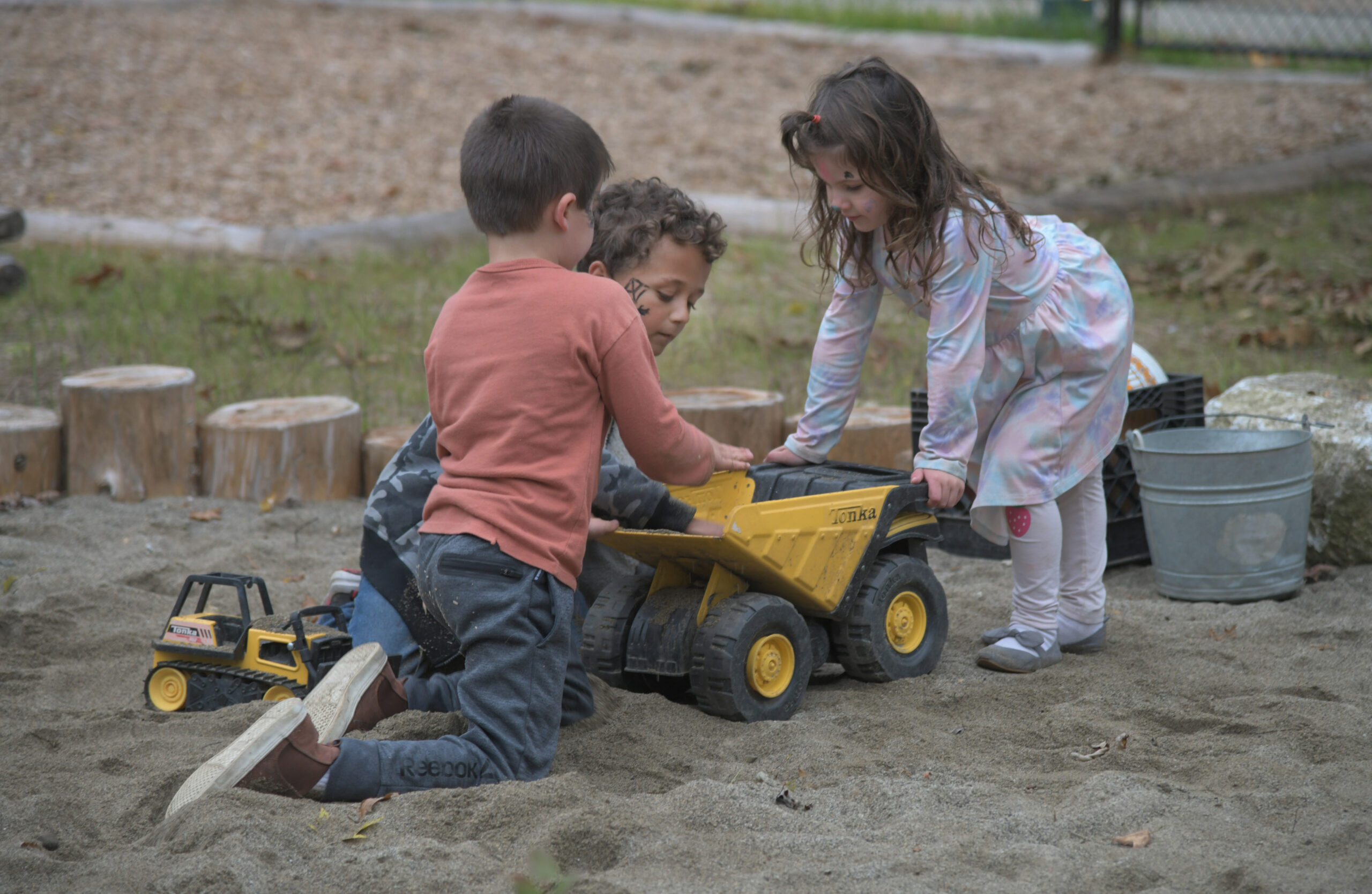 Three children happily playing in the sand